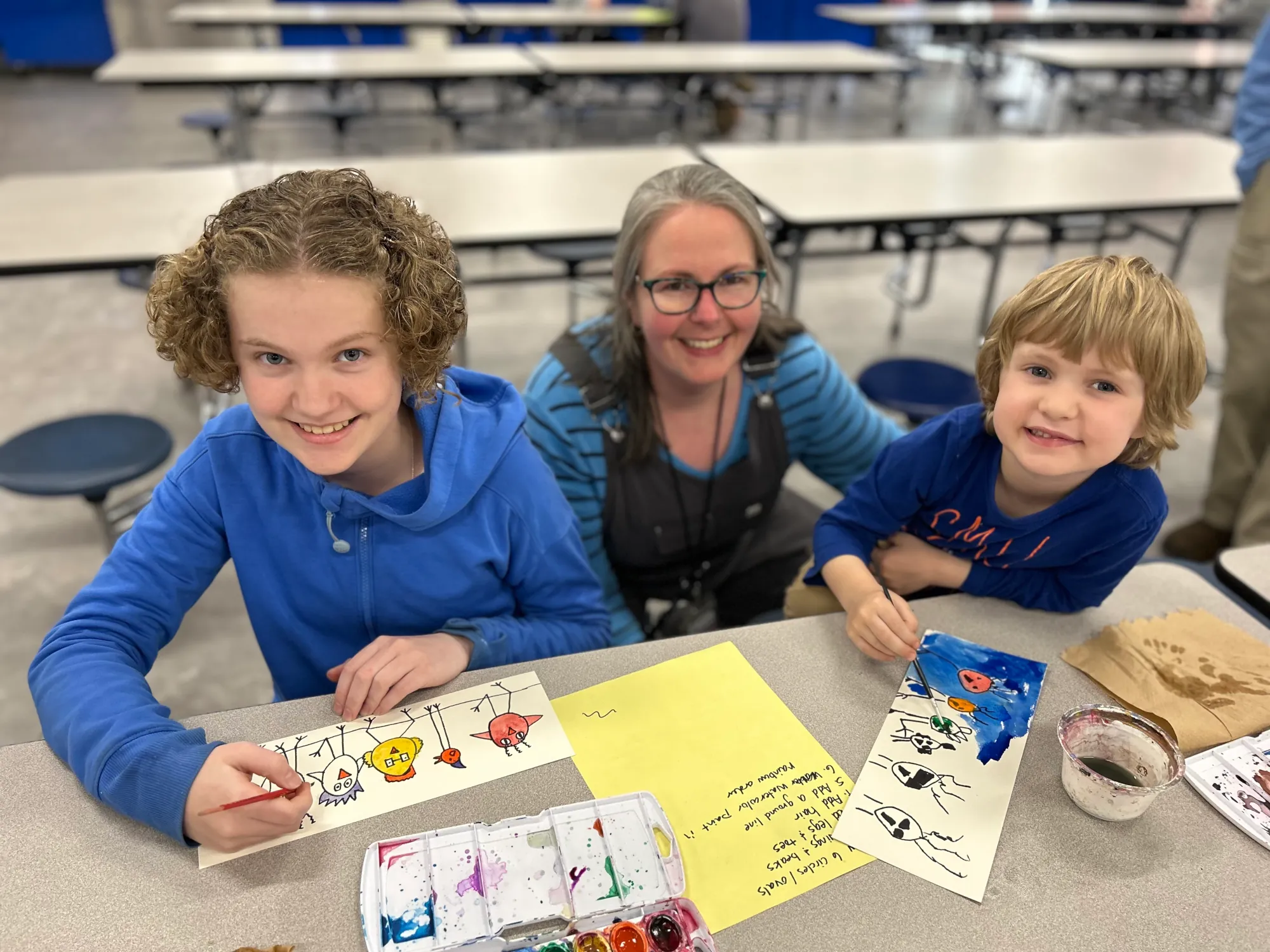 The Founder of Blue Goose sitting with 2 school aged children making art