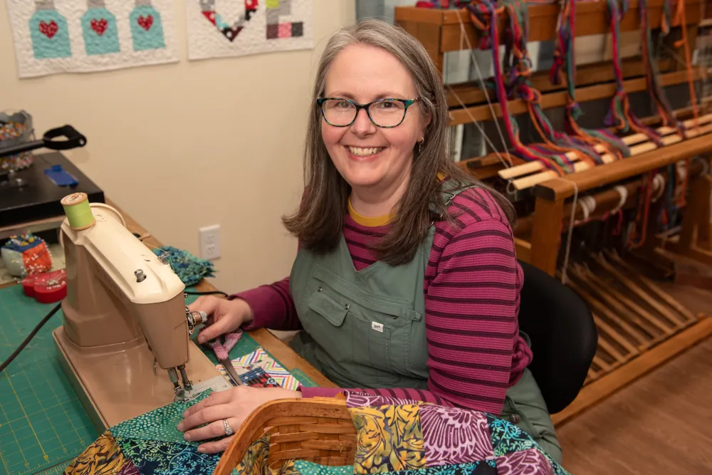 Founder of Blue Goose at a sewing machine smiling at the camera