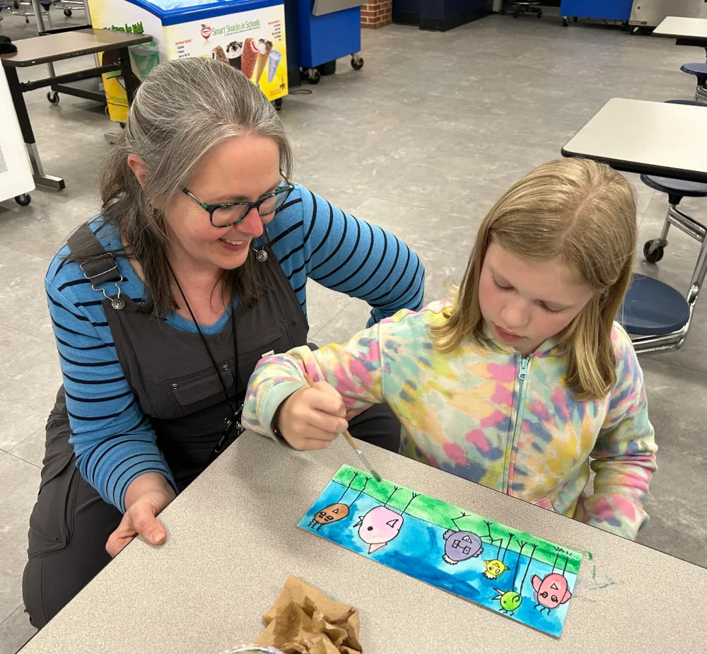 Founder of blue goose observing a child while they paint