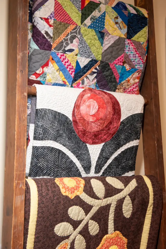 Several folded quilts hanging on a rack