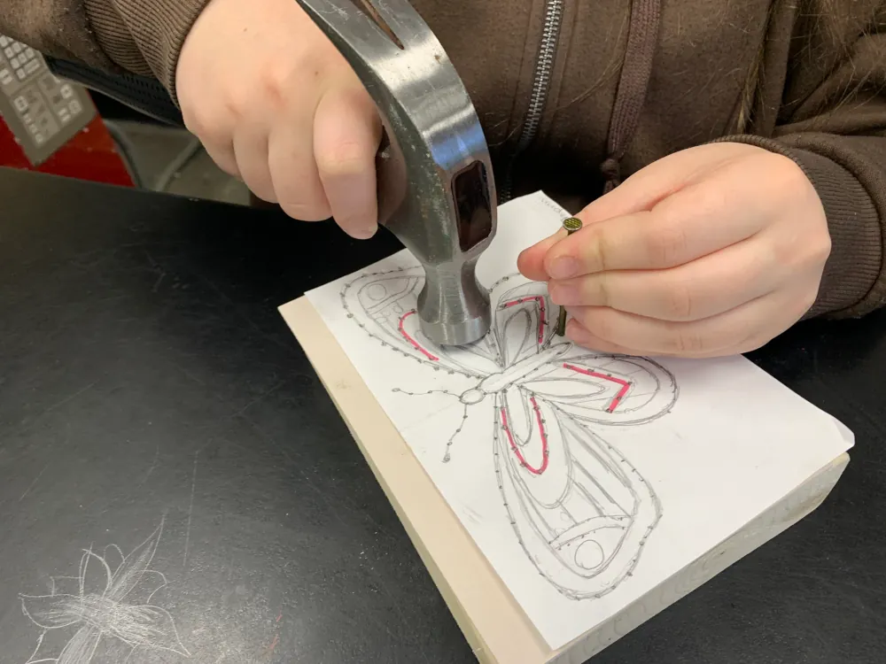 a close up of someone using a hammer to stitch a butterfly pattern