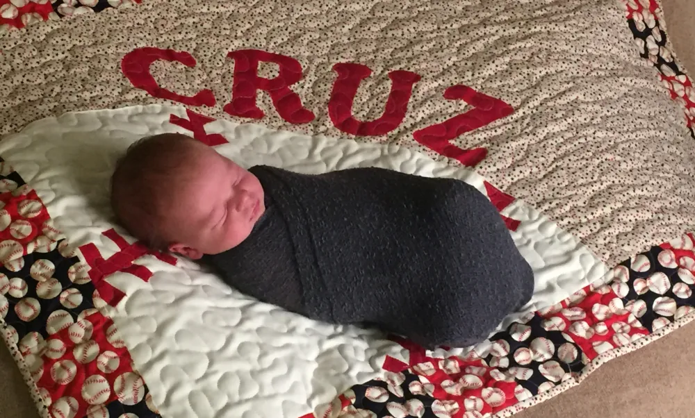 sleeping baby wrapped up and laying on a quilt