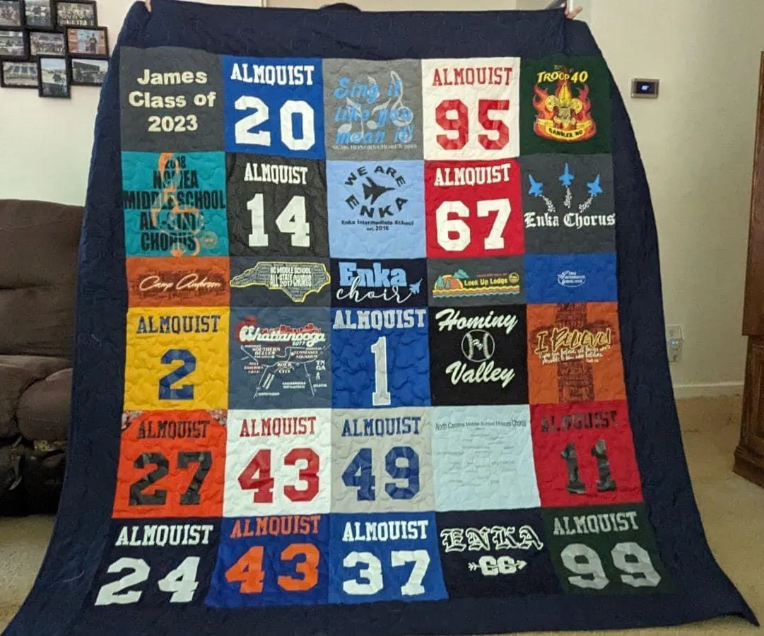 someone holding up a quilt made of tshirts with sport numbers