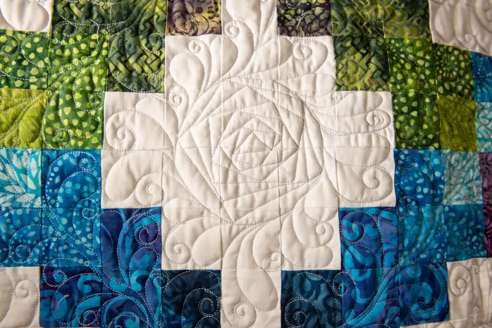 vintage style quilt with a diamond of blue and green surrounding a flower pattern